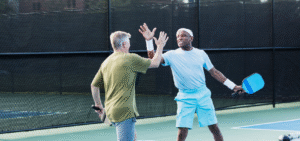 two senior men doing a high five while playing pickleball