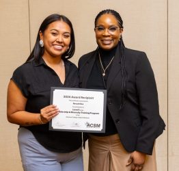 Two women smiling at the camera, one is holding a certificate